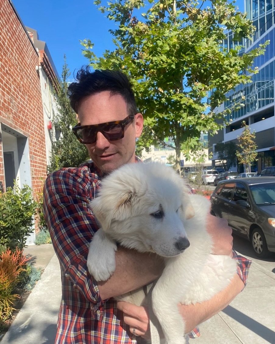 Houston Berry on a Los Angeles sidewalk, holding a fluffy white puppy